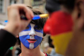 Greek and German soccer fans having faces painted